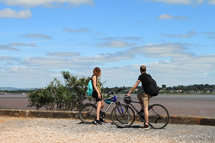 Man And Woman Cycling Along Gravel Path In Devon