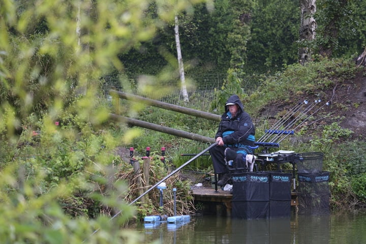 Man Sat Down Fishing In Rain By A Pond